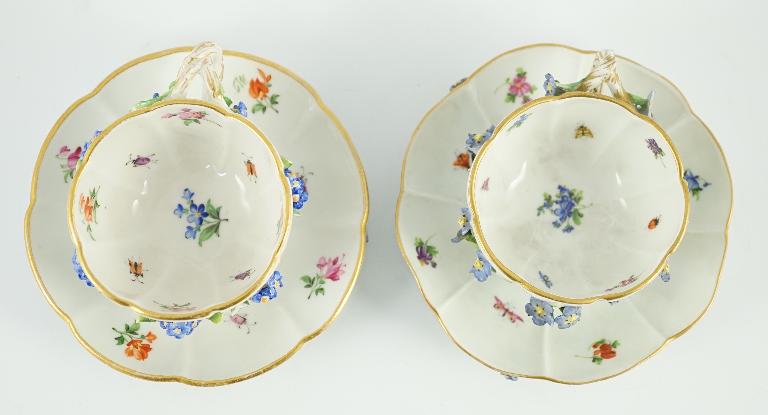 Two Meissen flower encrusted cups and saucers, 19th century, saucers 12cm wide, chips to flowers and leaves